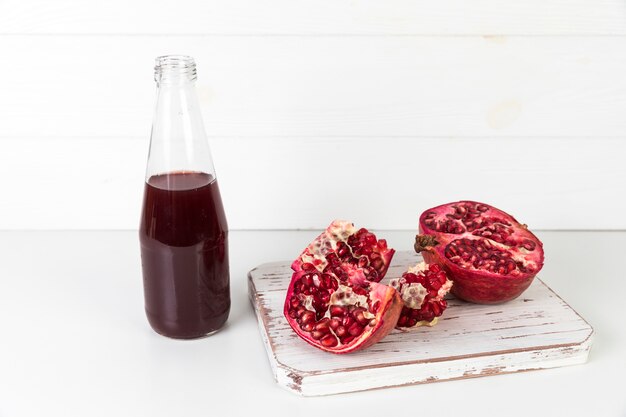 Foto frischer granatapfelsaft in der flasche auf tabelle