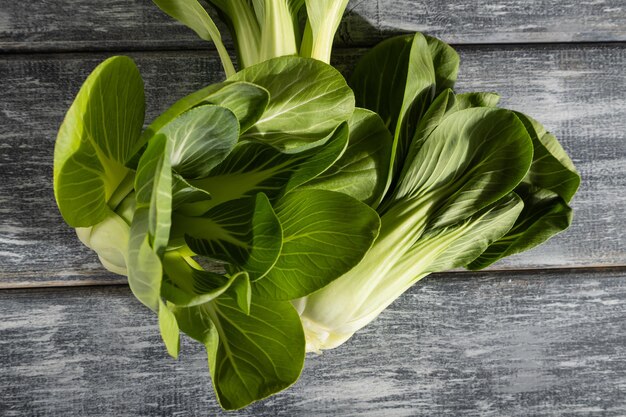 Frischer grüner Bok Choy oder Pac Choi Chinakohl auf grauem Holzhintergrund. Hartes Licht, Kontrast. Ansicht von oben, Nahaufnahme, flach.