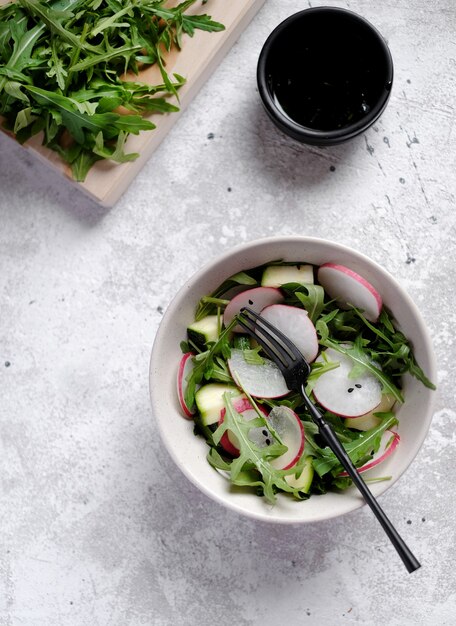 Frischer grüner Frühlingssalat mit Rucola und Rettich auf weißem Marmorhintergrund