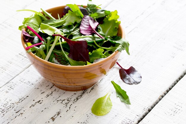 Frischer grüner gemischter Salat in einer Schüssel auf einem Holztisch