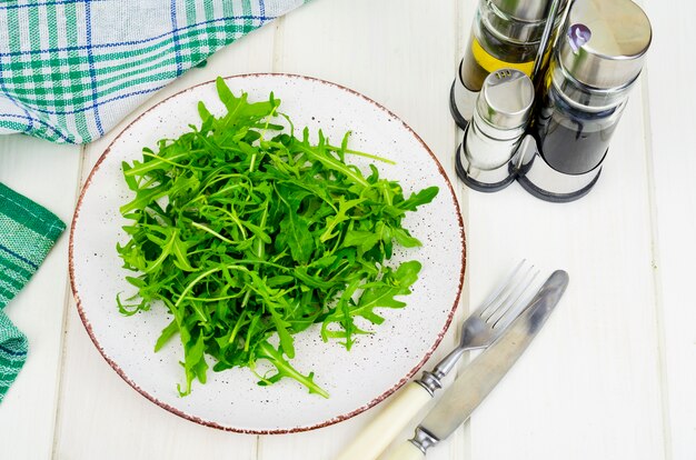 Frischer grüner Rucola auf Platte mit Olivenöl, Pfeffer und Salz