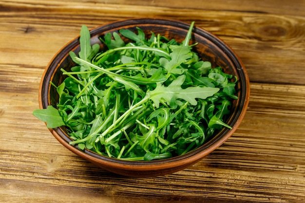 Frischer grüner Rucola in Keramikschale auf einem Holztisch Gesundes Essen oder vegetarisches Konzept