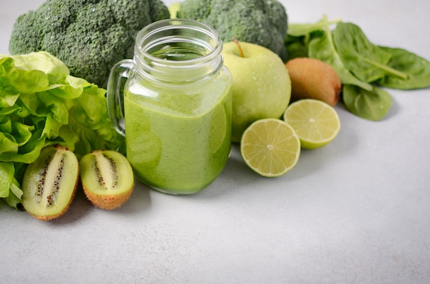 Frischer grüner Smoothie in einem Glas mit Bestandteilen