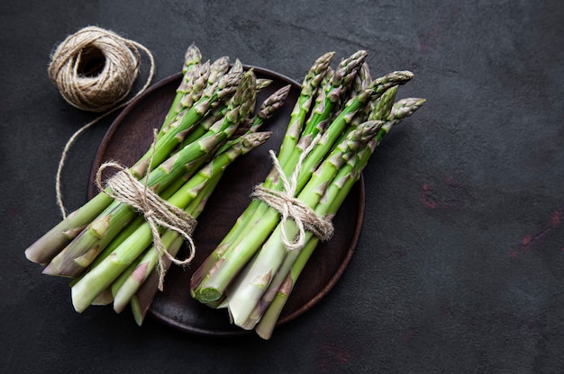 Frischer grüner Spargel auf schwarzem Betontisch. Flach liegen