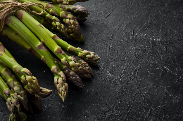 Frischer grüner Spargel auf schwarzem Steinhintergrund Gesundes Essen Draufsicht freier Kopierplatz