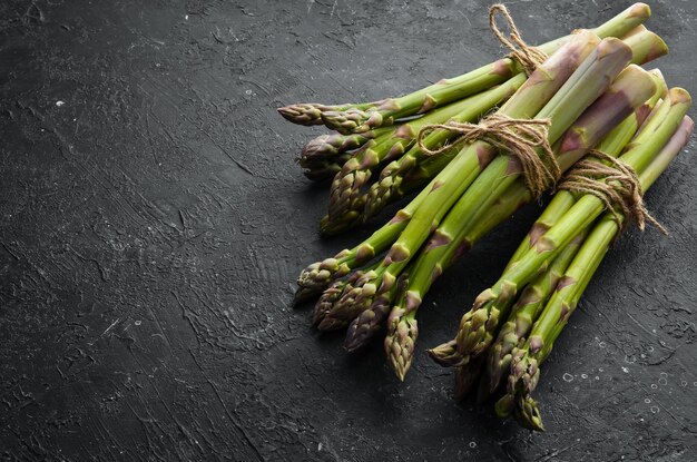 Frischer grüner Spargel auf schwarzem Steinhintergrund Gesundes Essen Draufsicht freier Kopierplatz