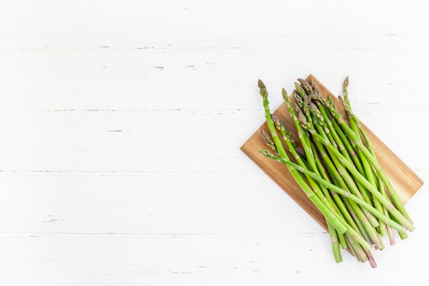 Frischer grüner Spargel auf weißer Holzoberfläche