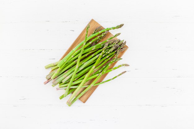 Frischer grüner Spargel auf weißer Holzoberfläche