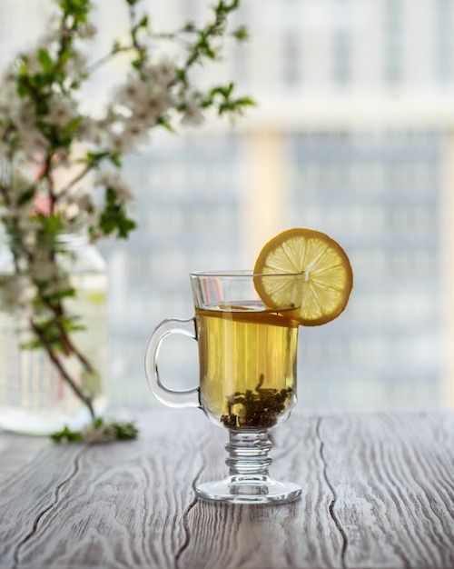 Frischer grüner Tee. Teetasse mit grünem Teeblatt auf dem Holztisch. Tee mit Zitrone