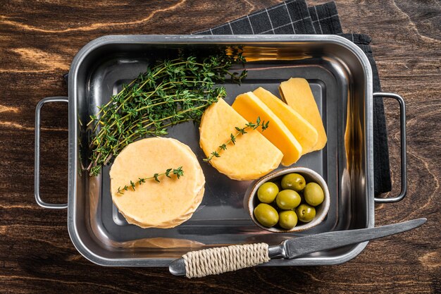 Frischer Halloumi-Schnittkäse im Küchentablett mit Thymian. Hölzerner Hintergrund. Ansicht von oben.