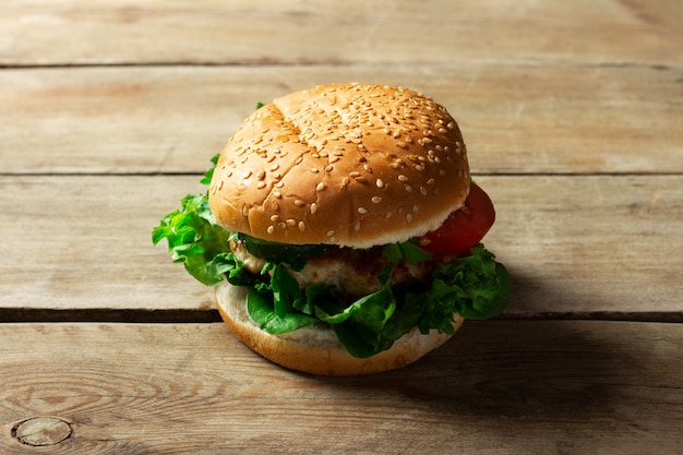 Frischer hausgemachter appetitlicher leckerer Burger mit Hühnchen auf Holztisch