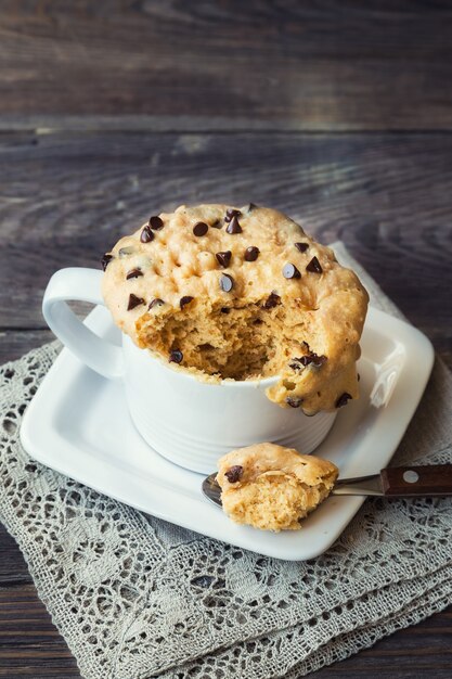 frischer hausgemachter Kuchen im Becher mit Erdnussbutter und Schokoladenstückchen auf rustikalem Holzhintergrund