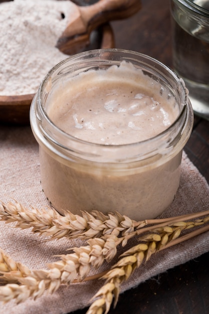 Frischer hausgemachter Sauerteig-Starter, eine fermentierte Mischung aus Wasser und Mehl, die als Sauerteig zum Brotbacken auf einem Holztisch verwendet werden kann