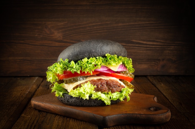 Frischer hausgemachter schwarzer Burger auf kleinem Holzschneidebrett