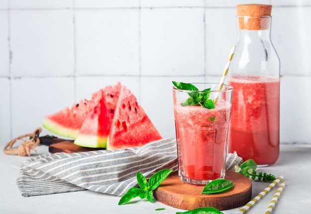 Frischer hausgemachter Wassermelonen- und Basilikum-Smoothie im Glas auf weißem Fliesenhintergrund