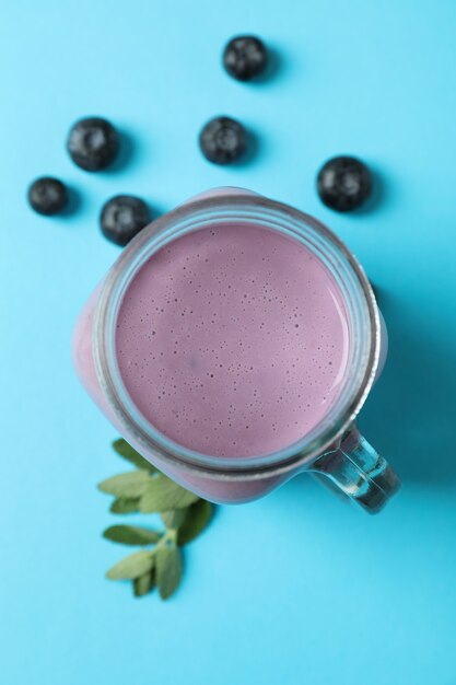 Frischer Heidelbeer-Smoothie und Zutaten auf blauem Hintergrund