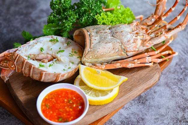 Frischer Hummer oder Hummer Meeresfrüchte mit Kräutern und Gewürzen Zitrone Koriander Petersilie Kopfsalat Salat Languste Essen auf Platte Hummer zum Kochen von Speisen und Meeresfrüchten Sauce