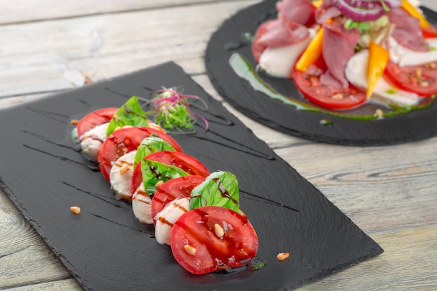 Frischer italienischer caprese Salat mit Mozzarella und Tomaten auf dunkler Platte