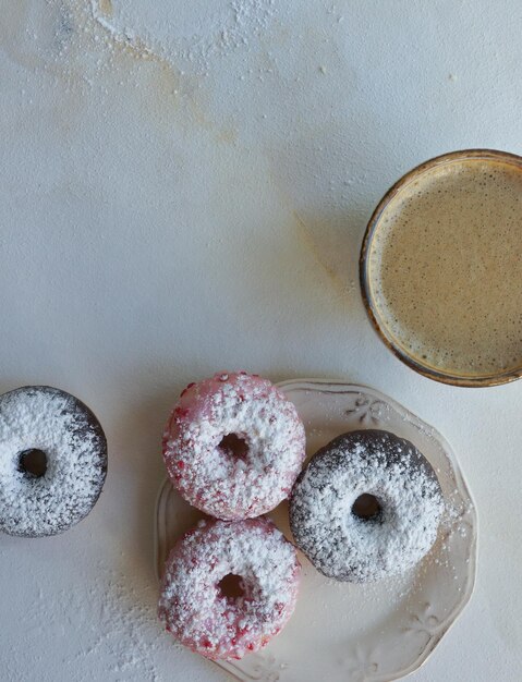 Frischer Kaffee und bunte Donuts auf weißem Marmortisch mit Cappuccino-Flachlage