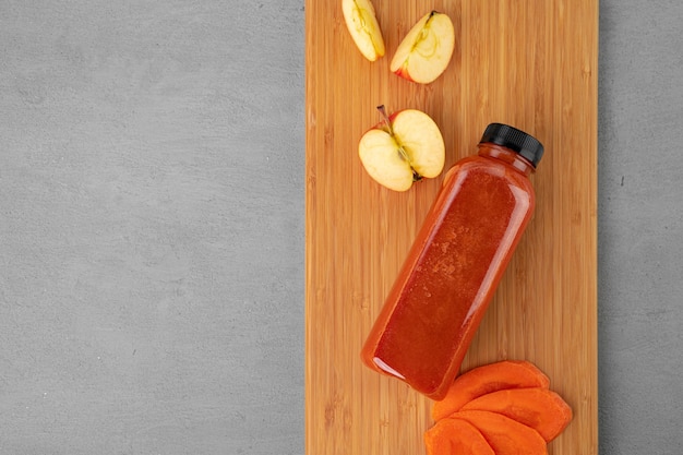 Frischer Karottensaft in Plastikflasche auf grauem Hintergrund