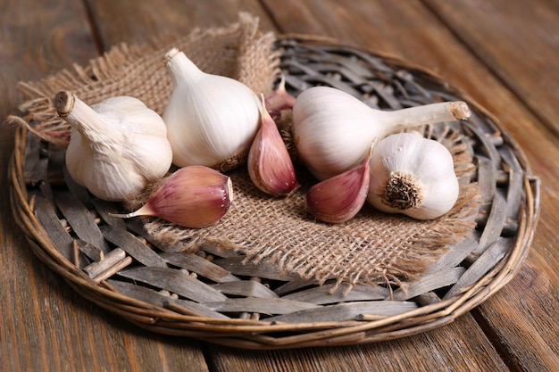 Frischer Knoblauch auf Korbmatte auf Holzhintergrund