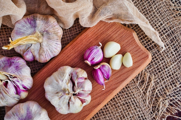 Frischer Knoblauch und Nelken auf einem Holzbrett in einem rustikalen Öko-Produktkonzept