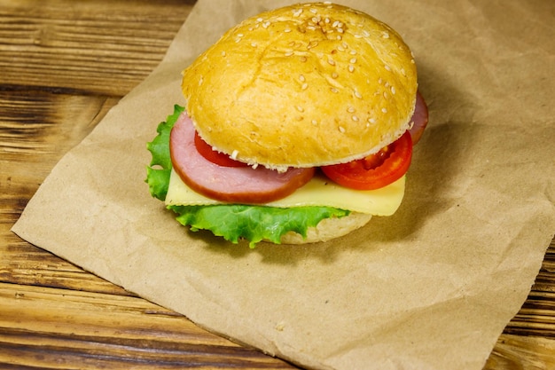 Frischer köstlicher hausgemachter Cheeseburger auf braunem Papier auf Holztisch