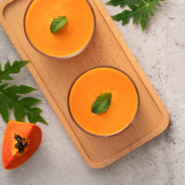 Foto frischer, köstlicher papaya-milch-smoothie im glasbecher auf grauem tischhintergrund für ein designkonzept für tropische früchte