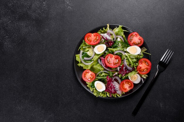 Frischer köstlicher vegetarischer Salat des gehackten Gemüses auf einem Teller auf einem dunklen Betonhintergrund