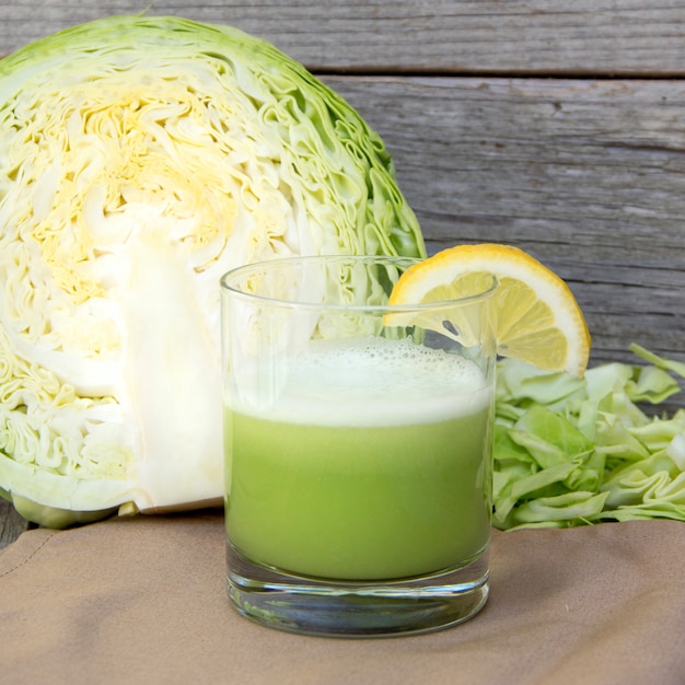 Frischer Kohlsaft und Kohl auf einem Holztisch schließen oben