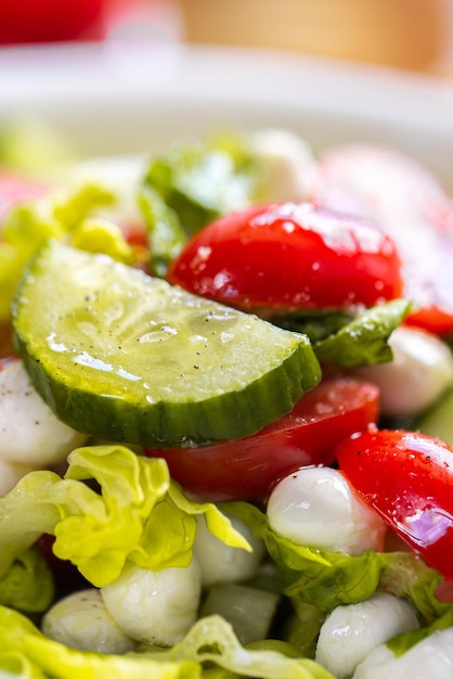 Frischer Kopfsalat Makroaufnahme. Salat mit Baby-Mozzarella-Kirschblättern Eisberg. Olivenöl im Salat.