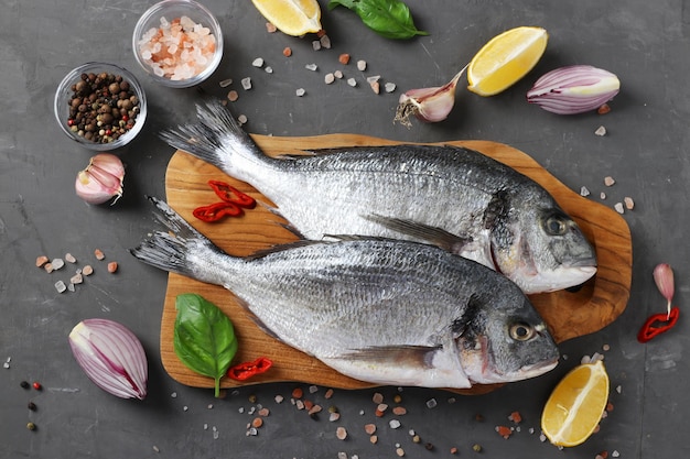 Frischer, küchenfertiger Dorado aus rohem Fisch mit Zutaten und Gewürzen wie Basilikum, Zitrone, Salz, Pfeffer