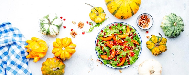 Frischer Kürbissalat mit gebackenem süßem Kürbissalat Rucola Granatapfel und Nüssen Gesunde vegane Hausmannskost Weißer Hintergrund Banner mit Draufsicht