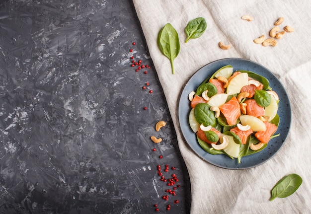 Frischer Lachs mit Ananas, Spinat und Acajoubaum in der blauen keramischen Platte auf einem schwarzen Beton.