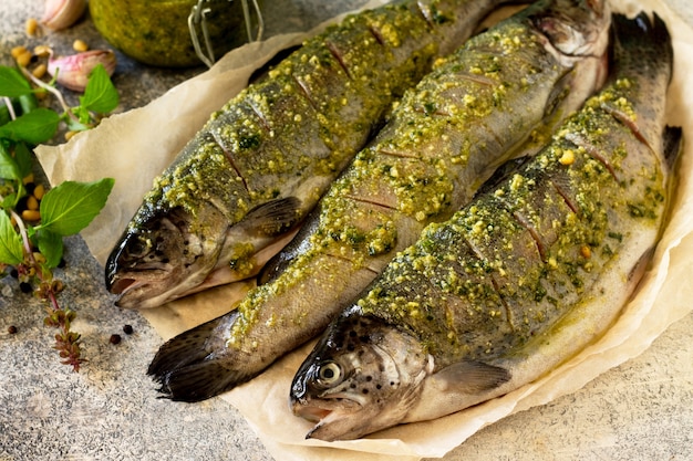 Frischer Lachsbacken Marinierter Fisch mit Pestosauce und kulinarischen Gewürzen auf einer grauen Steinplatte