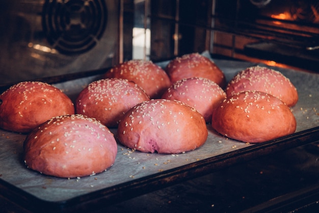 Frischer Laib rosa Burger mit Sesam im Ofen.