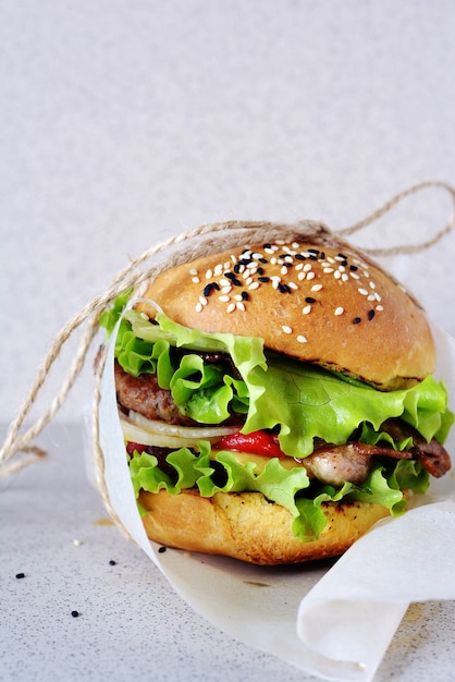 Frischer leckerer Hamburger (Burger) mit saftigem Schnitzel, gegrilltem Pfeffer, Zwiebel und Salat