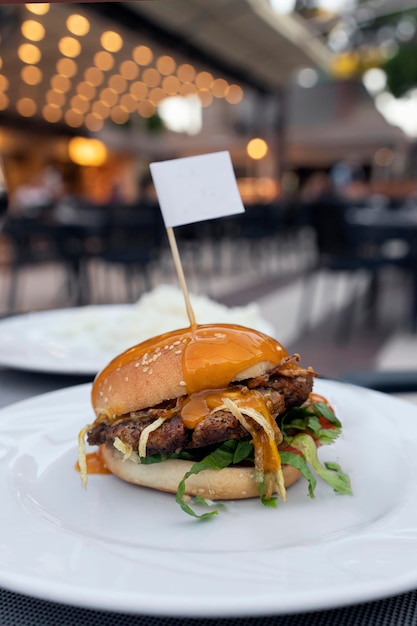 Frischer leckerer Hamburger mit Kotelettsalat und Röstzwiebeln und Senf auf einem Teller