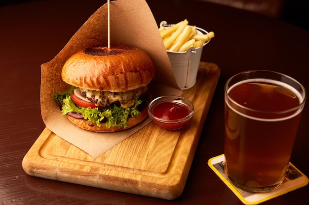 Frischer leckerer Rindfleischburger mit Pommes Frites und Bier auf Holztisch im Pub