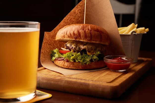 Frischer leckerer Rindfleischburger mit Pommes Frites und Bier auf Holztisch im Pub