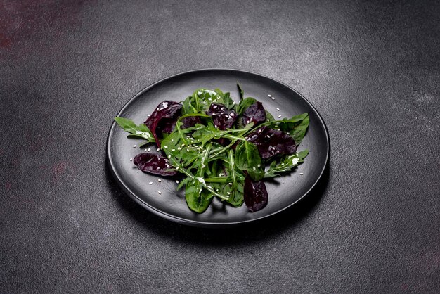 Frischer leckerer Salat mit Ärmeln Spinat und Rübenblättern mit Olivenöl auf einem schwarzen Teller Leckeres gesundes Essen