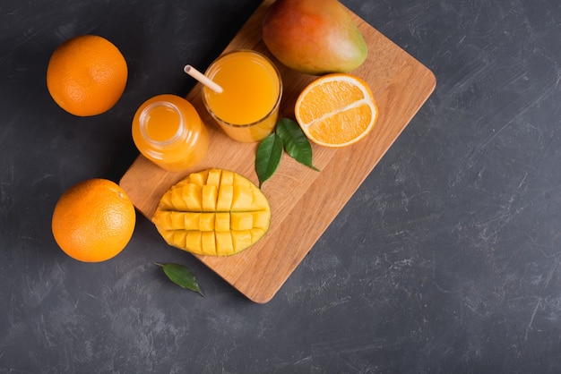 Frischer Mango-Orangensaft mit reifen Mangos und Orangenfrüchten auf Holzbrett