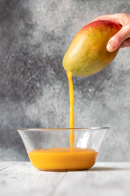 Frischer Mangosaft gießt in die Glasschüssel