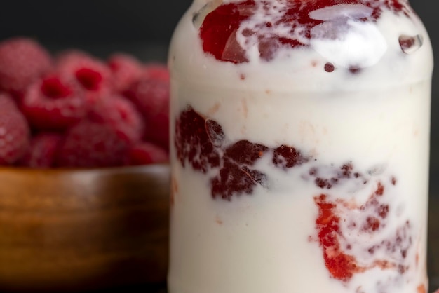 Frischer Milchjoghurt mit ganzen frischen Himbeeren. Ein Glas mit Himbeeren und frischem Joghurt aus Kuhmilch