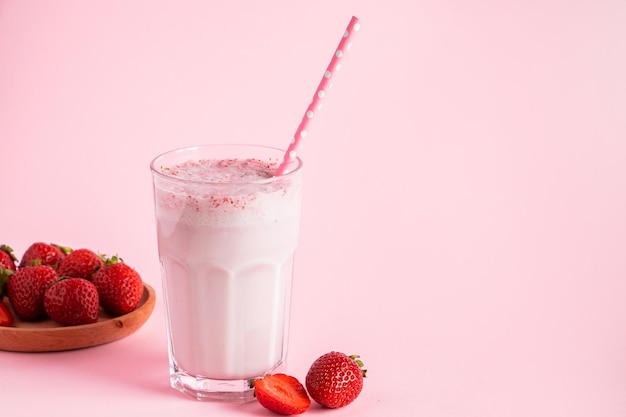 Frischer Milchshake mit Erdbeeren auf rosa Hintergrund Sommergetränk mit Beeren im Glas