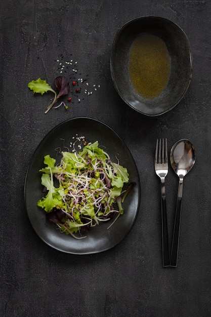 Frischer Mischbabysalat verlässt, Rosenkohl des organischen Porzellans mit Olivenöl auf dunklem Hintergrund