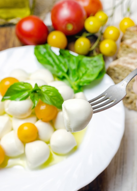 Frischer Mozzarella mit gelben Tomaten und Basilikum.