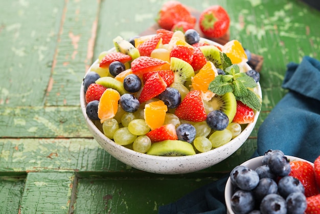 Foto frischer obstsalat, blaubeeren, erdbeeren, trauben, kiwi, orange. selektiver fokus