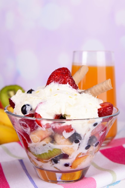 Frischer Obstsalat mit Eis in Schüssel und Saft auf hellem Hintergrund