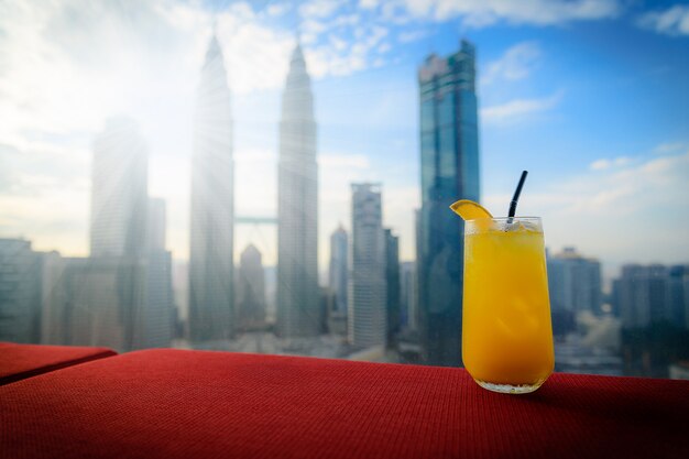 Frischer Orangensaft auf roter Tabelle mit Kuala Lumpur-Stadtskylinen in Malaysia.